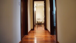 A hallway with wooden flooring and a chair in the distance. - Opulent Comfort Suites  (Colombo)