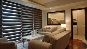 A modern living room with a sectional sofa, a coffee table, and a dining area. - Opulent Comfort Suites  (Colombo)