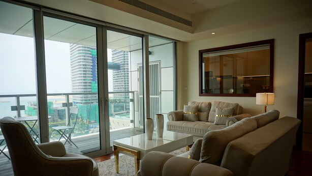 A modern living room with a sofa, armchair, and coffee table. Large windows offer a view of the cityscape. - Opulent Comfort Suites  (Colombo)