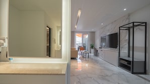 A modern living room with a large TV, marble flooring, and a minimalist design.