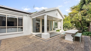 Ein modernes Haus mit Terrasse, großen Fenstern und einem Essbereich.