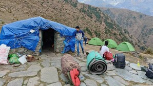 A mountainous campsite with tents and a stone structure. - Triund Trek and Camping (Dharamshala)