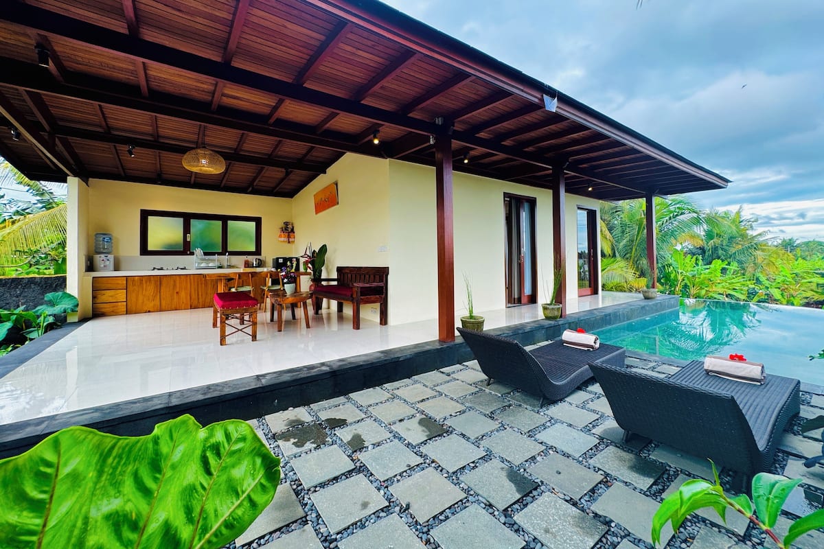 A modern villa with a covered outdoor area, a kitchen, and a swimming pool.