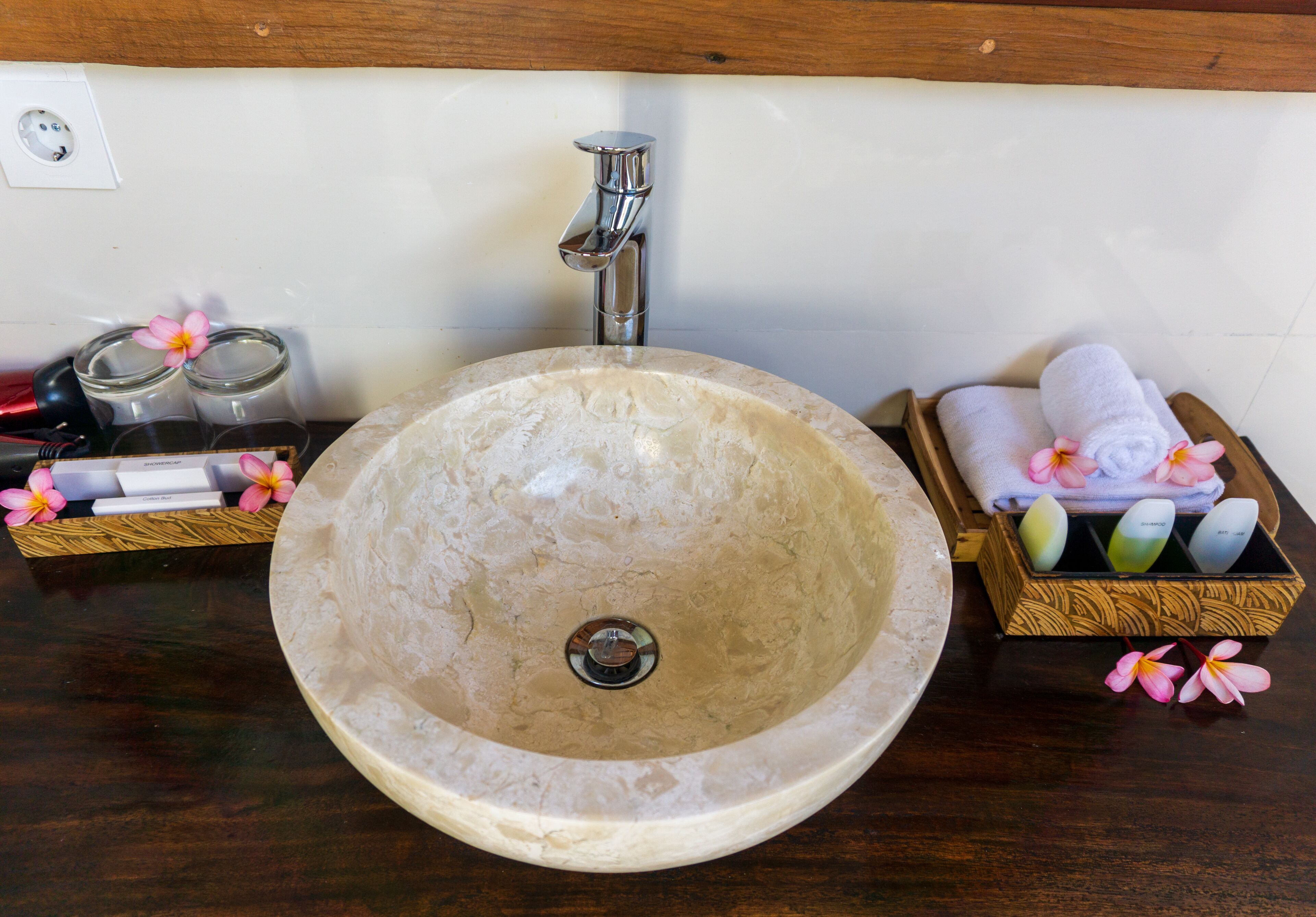 A bathroom sink with a marble basin, a faucet, and a wooden tray with towels and toiletries.