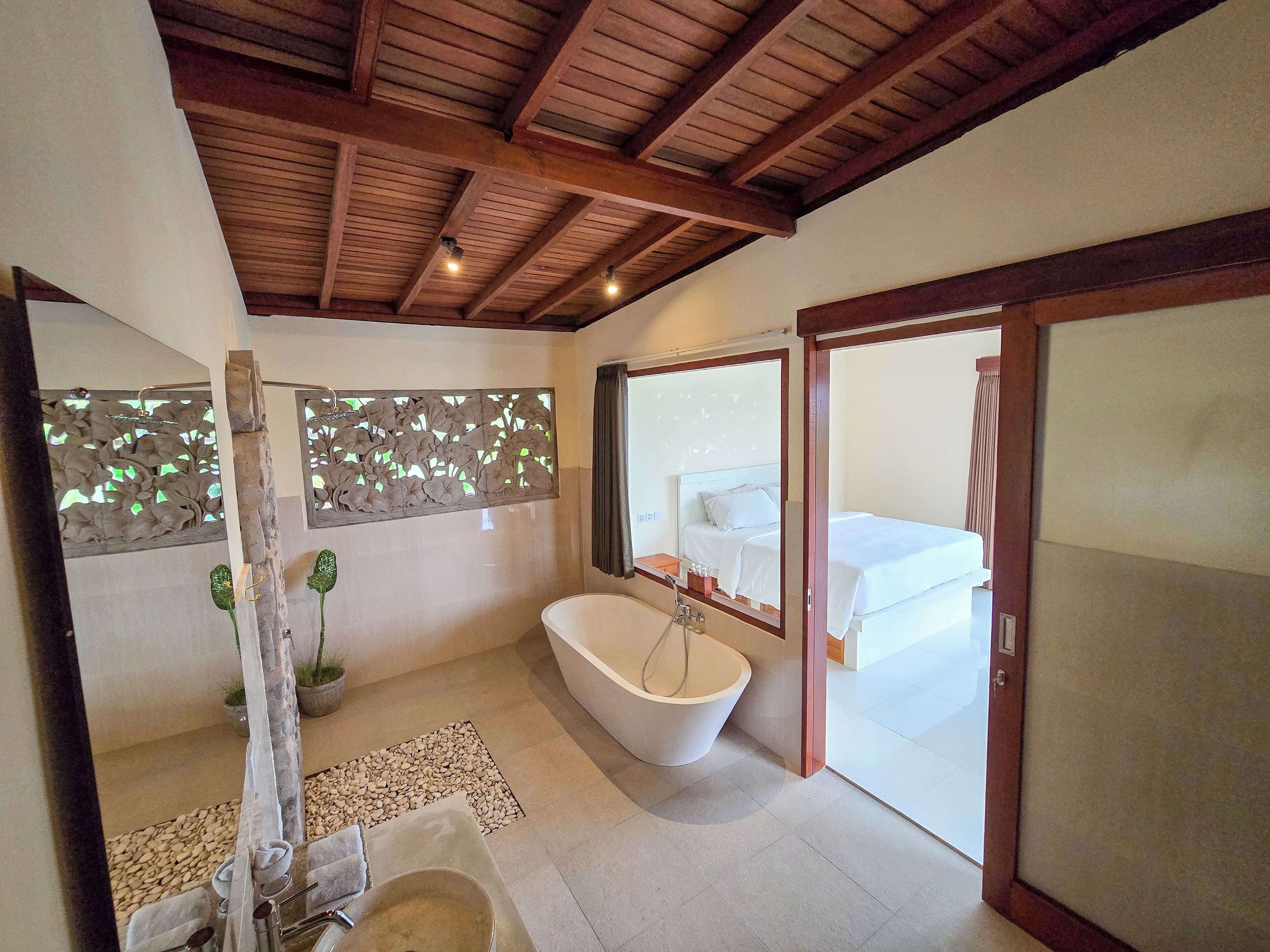 A modern bathroom with a freestanding bathtub, a large mirror, and a decorative wall panel.