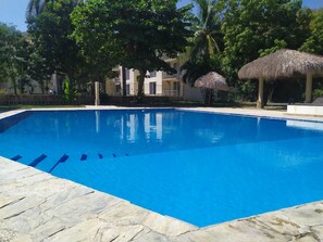 Una piscina con agua azul cristalina, rodeada de baldosas de piedra.