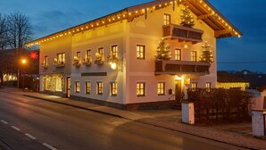 Ein zweistöckiges Hotel mit Balkonen, Weihnachtsdekoration und einem Schild, das es als Restaurant und Gasthof kennzeichnet.