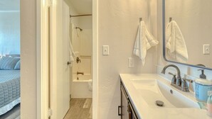 A modern bathroom with a large mirror, a sink, and a shower area. - Comfy and Cozy Studio for 2 (101 Spring Creek) (Kalispell)