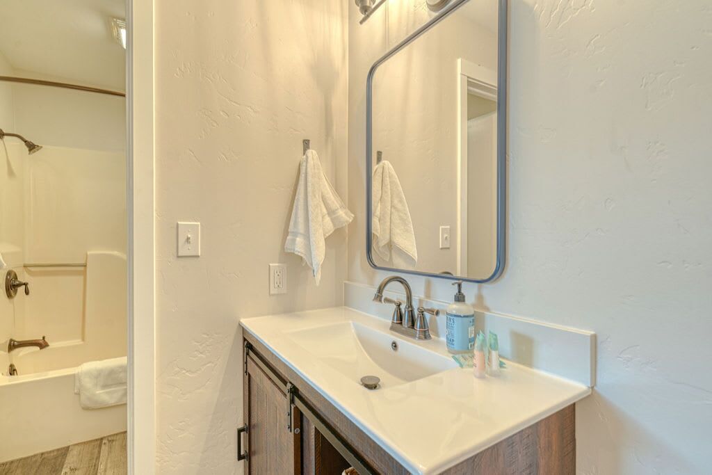 A bathroom with a white sink, a mirror, and a towel rack.