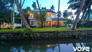 A two-story house with a stone wall and a small pond in front. - Kochi Backwater Resort (Ernakulam)