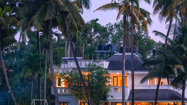 A two-story house with a swimming pool in front, surrounded by palm trees. - Kochi Backwater Resort (Ernakulam)