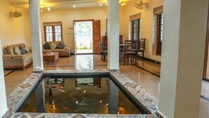 A spacious living area with a central water feature, a dining area, and a staircase leading to an upper level. - Kochi Backwater Resort (Ernakulam)