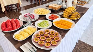 A buffet table with various fruits and breakfast items.