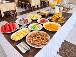 A buffet table with various fruits and breakfast items.