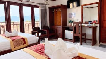 A hotel room with two beds, a desk, a chair, a television, and a view of the mountains.