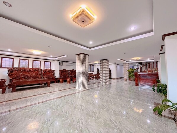 Um hall amplo com piso de mármore, um banco de madeira e uma escada.