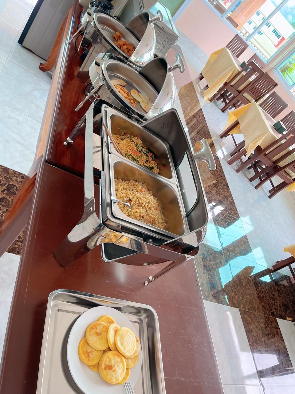 A buffet setup with various food items and a tray of pancakes.
