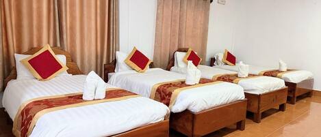 A hotel room with four wooden beds, each with white bedding and red pillows.