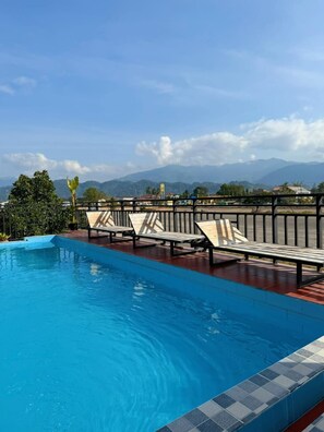 A swimming pool with lounge chairs and a view of mountains. - Vangvieng Sisavang Mountain View Hotel (Vang Vieng)
