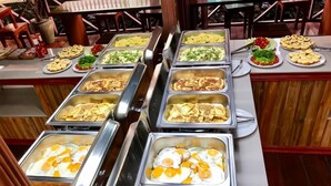 Un buffet proposant une variété de plats, notamment des œufs, des salades et des viennoiseries.