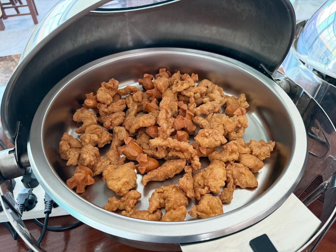 A stainless steel bowl filled with fried chicken pieces.