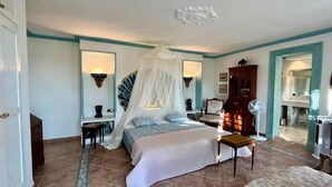 A bedroom with a bed, bedside tables, a chair, a fan, and a wardrobe. - Inmitten Eines Mediteranen Gartens, Terrassiert, Befindet Sich das Appartment (Santa Eulària des Riu)