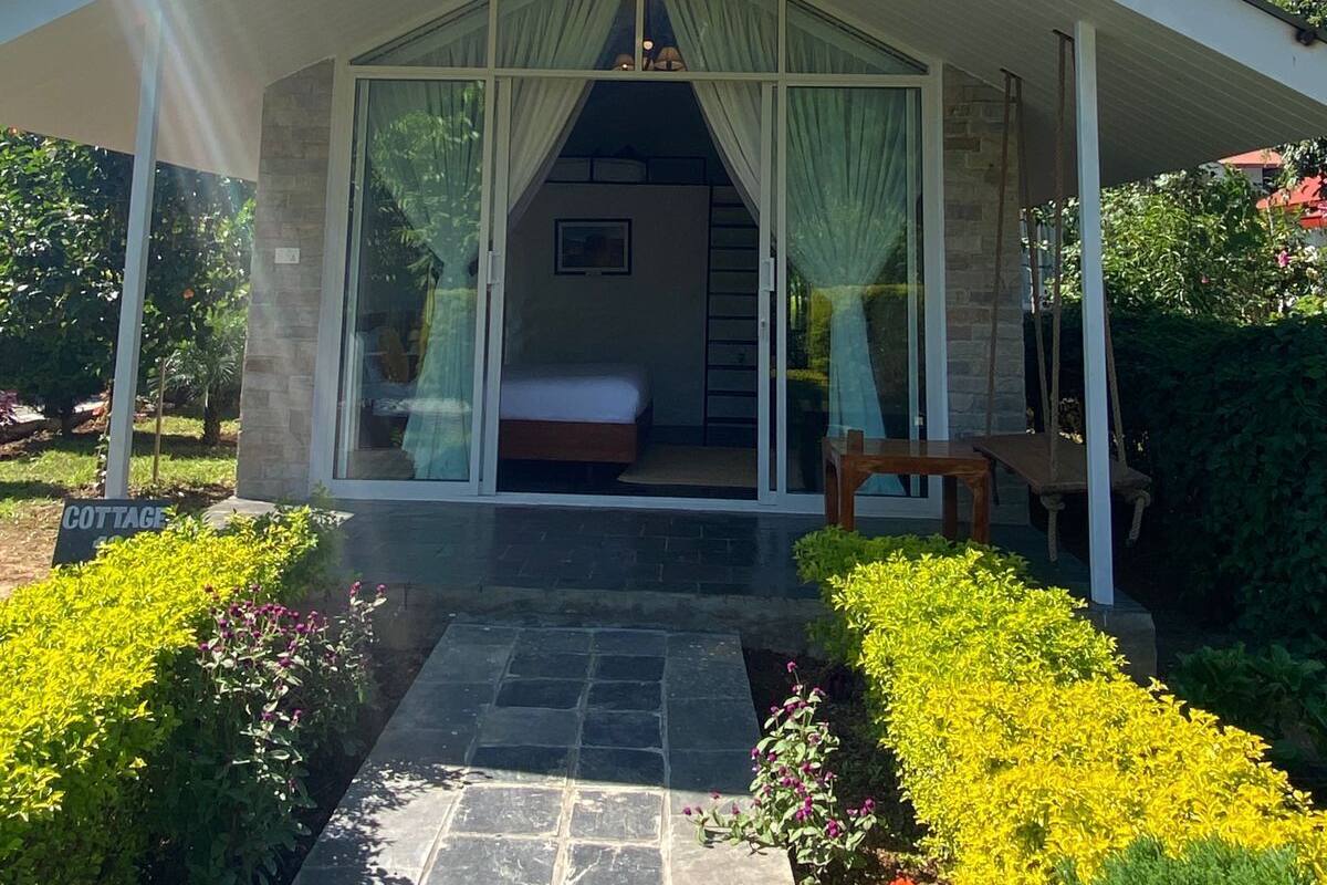 A cottage with a covered patio, a bed, and a small table.