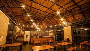A spacious indoor area with wooden tables and benches, a staircase, and a bar area.