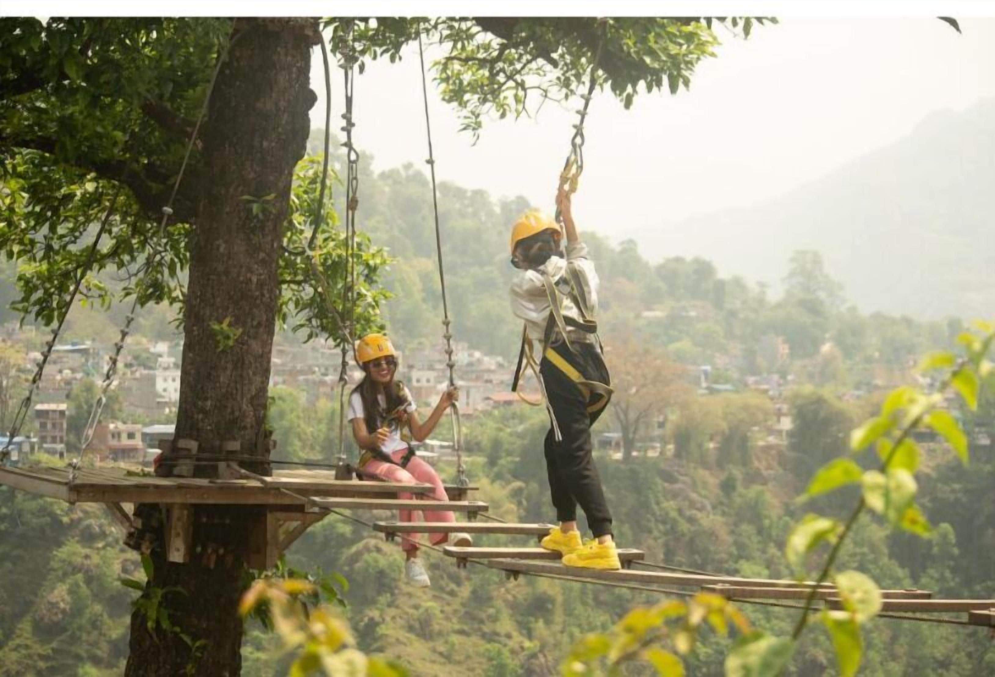 A person on a zip line course with another person assisting.