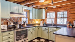 A kitchen with light green cabinets, a checkered floor, and a wooden ceiling. - Charming & Cozy Cabin w/ Screened Porch (Stone Ridge)