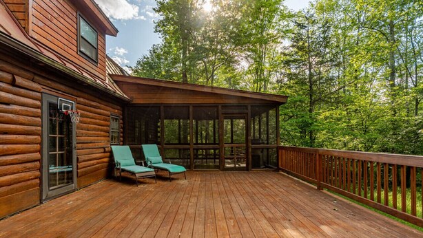 A wooden deck with two green lounge chairs and a covered area. - Charming & Cozy Cabin w/ Screened Porch (Stone Ridge)