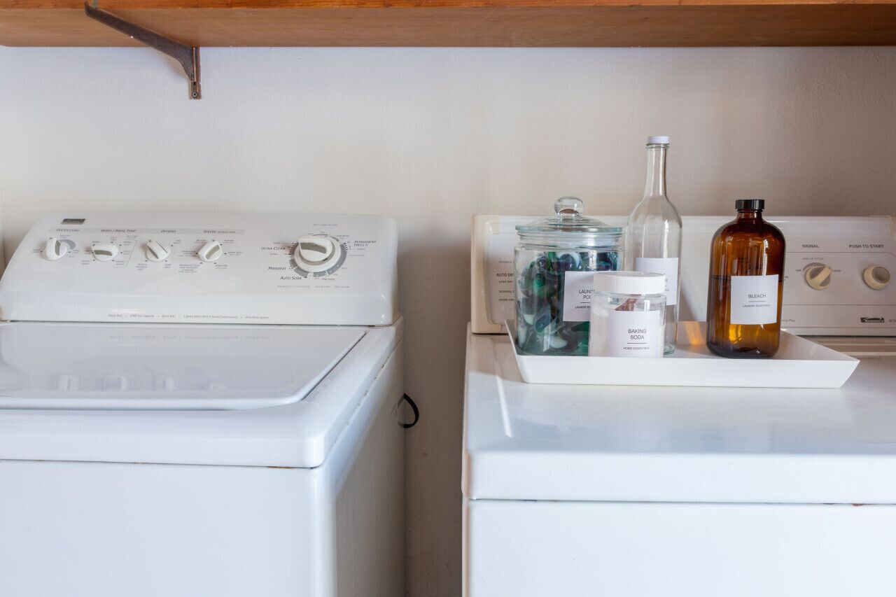 A laundry area with two washing machines and a drying rack.