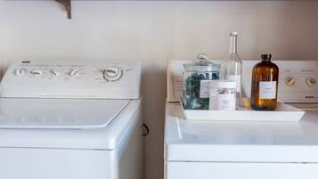 A laundry area with two washing machines and a drying rack.