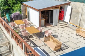 An outdoor patio with tables and chairs, a small kitchen area, and a covered seating space.
