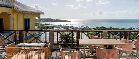 A terrace with wicker furniture overlooking a coastal view.