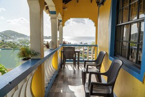 Ein Balkon mit Blick auf das Meer und eine hügelige Landschaft.