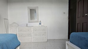 Una habitación con dos camas, un tocador, un espejo y una puerta.