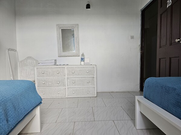 Una habitación con dos camas, un tocador, un espejo y una puerta.