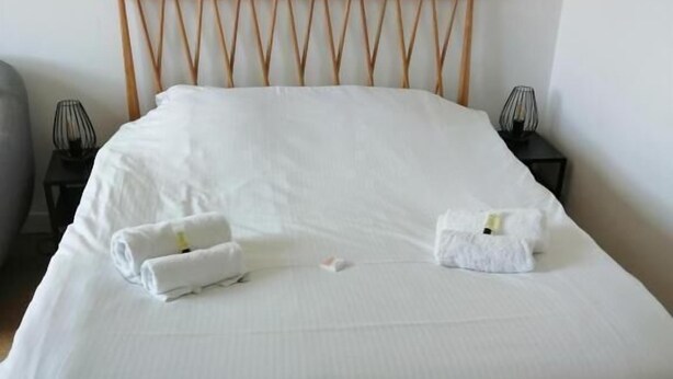 A neatly made bed with white linens and two towels placed on it. - Studio Tout Confort Giena-sils (Caen)