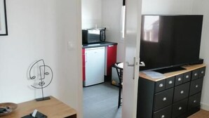 A compact living space with a kitchenette, a dining area, and a TV. - Studio Tout Confort Giena-sils (Caen)