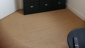 A television on a wooden stand in a corner with a black storage unit below it. - Studio Tout Confort Giena-sils (Caen)