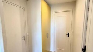 A narrow hallway with wooden flooring and white doors. - Grand Logement Jupiter-sils (CAEN)