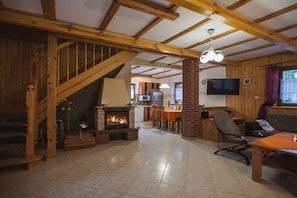 A wooden interior with a fireplace, a dining area, and a TV mounted on the wall.