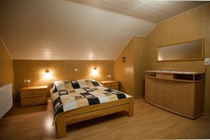 A bedroom with a wooden bed, nightstands, a dresser, and a mirror. - Four -anniversary Type C (Dzwirzyno)