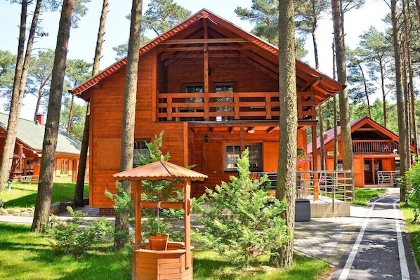 A wooden cabin with a balcony, surrounded by trees.
