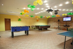 Sala de recreación con mesa de fútbol de mesa, mesa de billar y mesa de tenis de mesa.