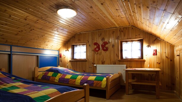 A wooden cabin bedroom with two beds, a desk, and a radiator. - Four -anniversary Type B (Dzwirzyno)