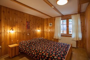 Una habitación con paneles de madera, una cama, una ventana con cortinas e iluminación en la pared.