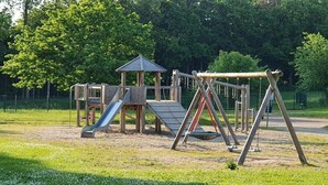 A playground with a slide, swings, and a climbing structure. - Holiday Home by the Baltic Sea with Terrace (Ostseebad Rerik)