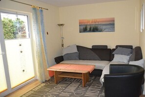 A living room with a sofa, a small table, a lamp, and a painting on the wall. - Holiday Home by the Baltic Sea with Terrace (Ostseebad Rerik)
